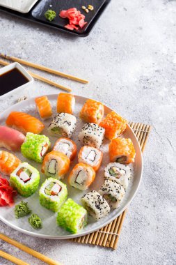 Çeşitli taze ve lezzetli suşi ahşap sopa ile beyaz kayrak ayarlamak, sos ışık taş zemin, düz üzerinde yatıyordu