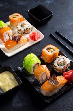 Siyah barut barut sopa, sos ve düz siyah taş zemin üzerine nori ile ayarlamak çeşitli taze ve lezzetli suşi yatıyordu