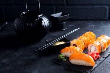 Siyah demir demlik ve siyah taş masada kayrak plaka üzerinde ayarla suşi ile Asya gıda arka plan