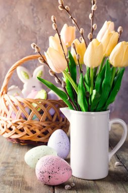 Ahşap bir masa üzerinde bir vazo ve Paskalya renkli yumurta Sarı laleler. Hediye ve Paskalya yumurtası.