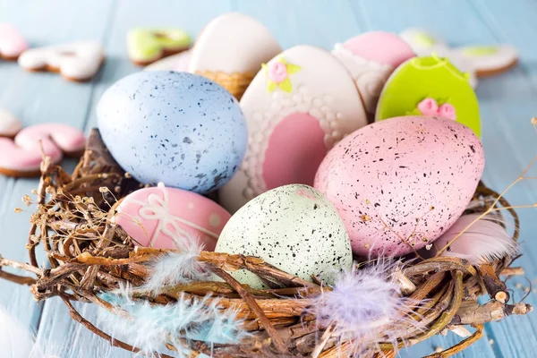 Kolorowe ciasteczka jaja wielkanocne i pisanki w drewniane gniazdo na niebieskim tle drewnianych, z bliska — Zdjęcie stockowe