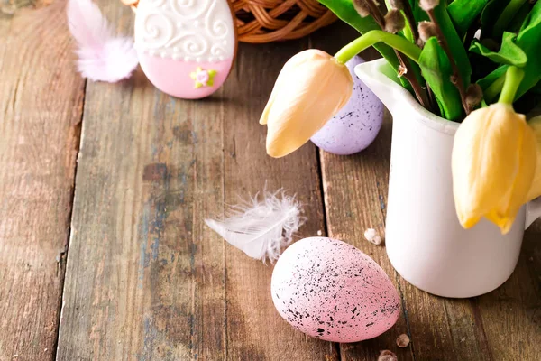 Gele tulpen in een vaas en Pasen kleurrijke eieren op een houten tafel. Gave en Pasen eieren. — Stockfoto