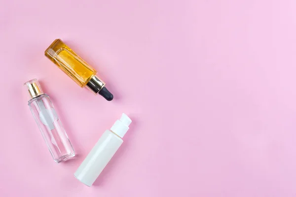 Butelki i słoiki z naturalnymi kosmetykami, kremem i olejami na różowym tle. Widok z góry — Zdjęcie stockowe