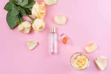 Pembe arka planda çiçekli parfüm şişeleri. Parfümeri, kozmetik, parfümeri koleksiyonu. Düz yatıyordu