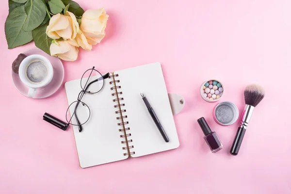 Workplace mockup with notebook, glasses, roses and accessories on pink background top view. Flat lay with coffee copy space. Feminine working style concept. — Stock Photo, Image