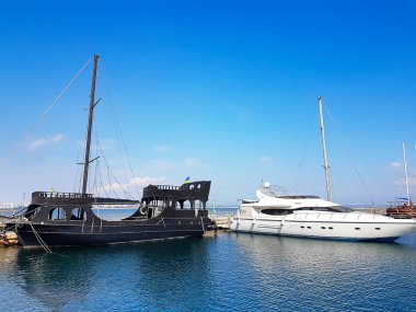 Odessa, Ukrayna. 15.03. 2019. Turistler için siyah ahşap eski gemi ve Deniz limanında modern bir beyaz yat.