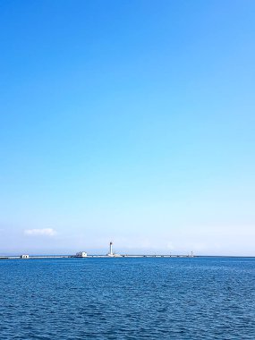 Bir kargo limanının arka planında denizde deniz feneri. Karadeniz. Odessa Deniz Limanı.