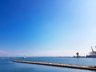 Bir kargo limanının arka planında denizde deniz feneri. Karadeniz. Odessa Deniz Limanı.
