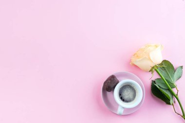 Taze kahve fincan ı ve pastel pembe arka plan üzerinde bej kokulu güller, düz yatıyordu