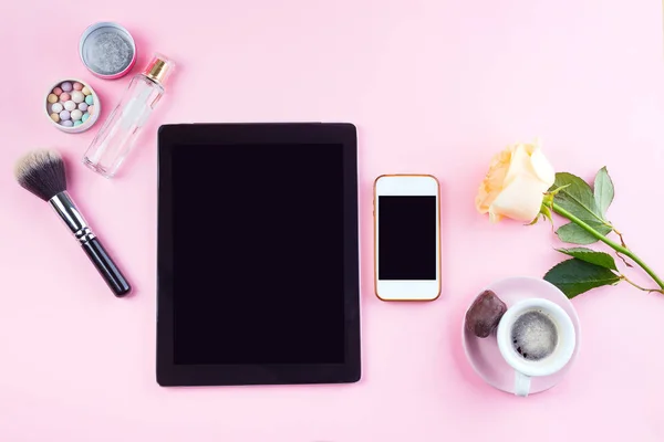 Platt låg uppsättning av tablett och telefon med kopp kaffe, glas, ros och parfym på rosa, mock up — Stockfoto