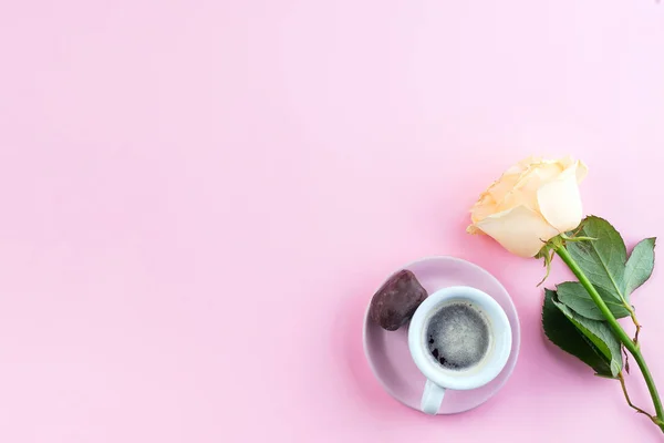 Xícara fresca de café e uma rosa fragrante bege em um fundo rosa pastel, flat lay — Fotografia de Stock