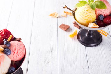 Ahşap arka planda çilek, çikolata ve nane ile renkli dondurma kepçeve tatlar