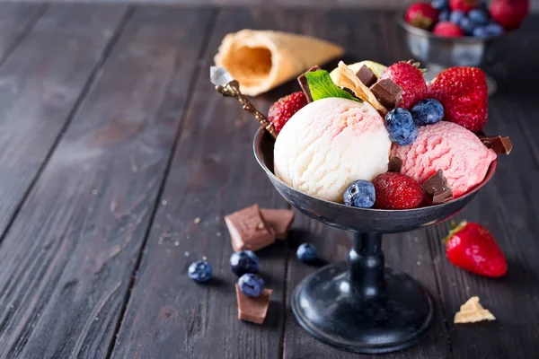 Conjunto de cucharadas de helado de diferentes colores y sabores con bayas, chocolate sobre fondo oscuro — Foto de Stock