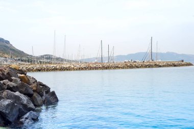 renkli taşların sualtı, mavi deniz ve balıkçı teknelerinin Turgutreis limanına demirlemiş görünümü, Bodrum, Muğla, Türkiye.