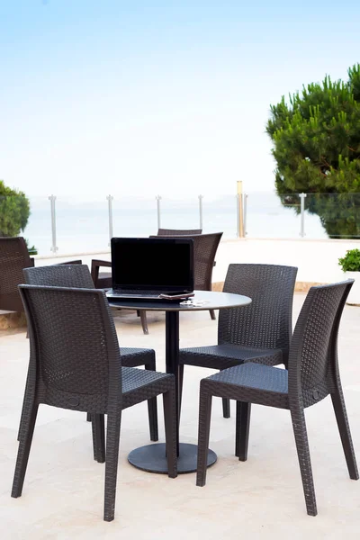 Comfort workplace. Laptop computer on cafe table outdoor with view on the sea