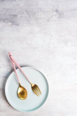 Taş arka plan üzerinde mavi plaka ile yeni lüks Altın çatal. Üst te. Bir düğün, doğum günü veya parti için bir festival masası için pembe bıçak ve çatal.