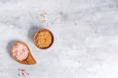 Ahşap kase üst görünümünde tuz ve şeker. Himalaya pembe kaya tuzu ve çiğ şeker kamışı.