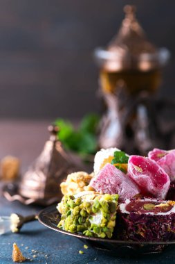 Koyu bir arka plan üzerinde nane ile türk lokum ve siyah çay çeşitli parçalar ile Kase.
