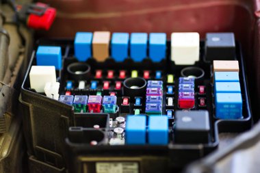 Araba sigorta kutusu yakın çekim. Farklı sigortalar birden fazla satır, bir konektör ve görünür bir röle parçası.