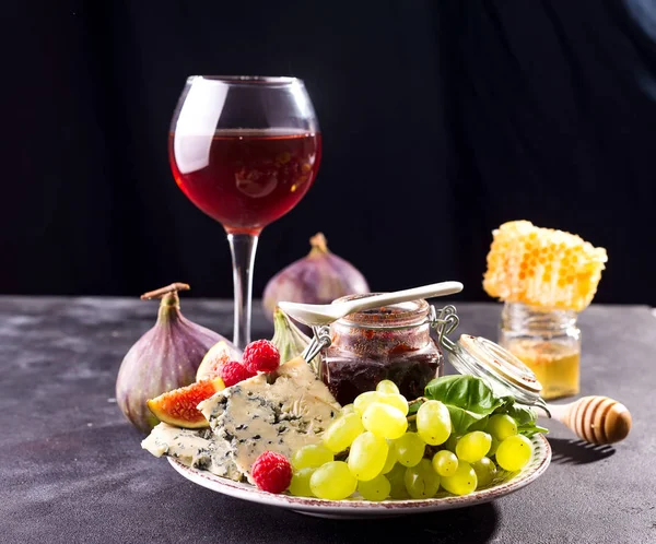 Taş arka planda gözlük kırmızı şarap ile peynir, çilek ve üzüm çeşitleri. Kopyalama alanı