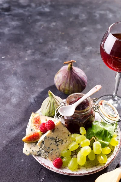 チーズ、ベリー、ブドウの品揃えと赤ワインをグラスに入れます。石の背景に。スペースのコピー — ストック写真