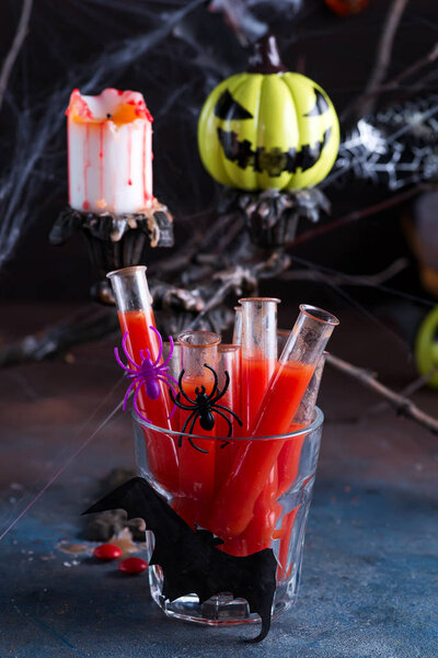 Bloody cocktail in glass tubes for Halloween party celebration. Black stone background