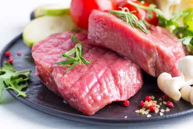 Mermer bir arka plan üzerinde bir tavada taze sebze ile kemik çiğ sığır eti biftek, üst görünümü