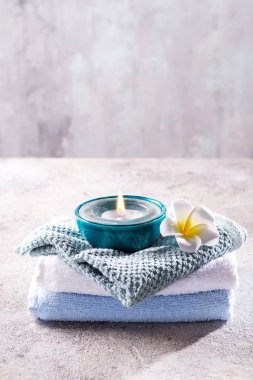 Spa resort terapi kompozisyonu. Yanan mumlar, havlu ve çiçek bir taş arka plan üzerinde, kopya alanı
