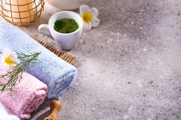 Asciugamani di colore con fiore, cucchiaio di sale, su tappetino di bambù, trattamento spa bagno e tè verde sul tavolo di pietra, spazio copia — Foto Stock