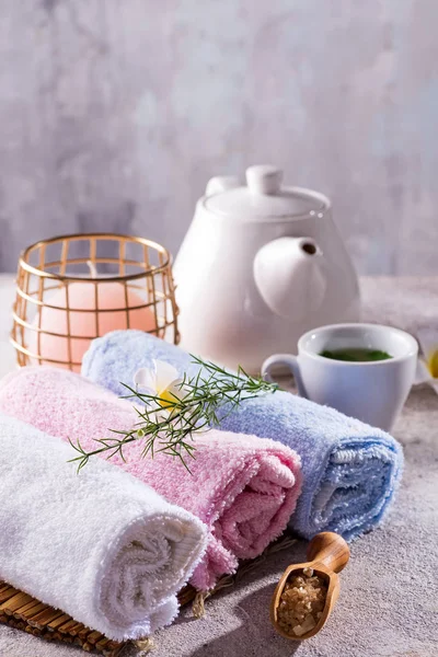 Asciugamani di colore con fiore, cucchiaio di sale, su tappetino di bambù, trattamento spa bagno e tè verde sul tavolo di pietra, spazio copia — Foto Stock