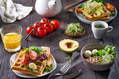 Avokado, yumurta, mikro yeşil ve portakal suyu ve ahşap masadaki çayla domatesli Belçika Waffle 'ları. Sağlıklı yemek ya da kilo vermek için mükemmel bir kahvaltı. Avokado sandviçi.