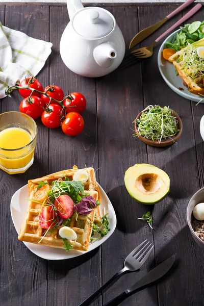 Waffles belgas com abacate, ovos, micro verde e tomates com suco de laranja e chá em mesa de madeira. Pequeno-almoço perfeito para alimentos saudáveis ou perder peso. Sanduíche de abacate . — Fotografia de Stock