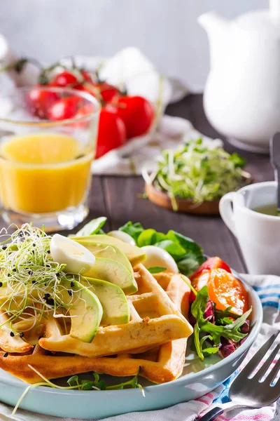 벨기에 사람들은 아보카도 , 달걀 , 마이크 로 녹색 및 도마도 나무 식탁에 오렌지 주 우스 를 바른 와플 을 가지고 있다. 건강에 좋은 음식을 위한 완벽 한 아침 식사나 체중 감량. 아보카도 샌드위치. — 스톡 사진
