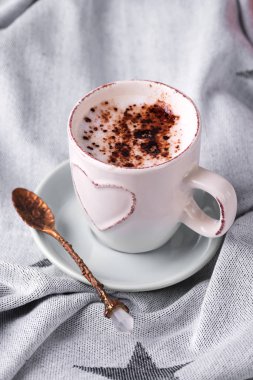 Yatakta battaniyesinde çikolata olan bir fincan kahve içmek.