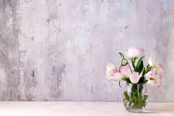 Eustoma flores em vaso na mesa perto da parede de pedra, espaço para texto. Branco para cartões postais — Fotografia de Stock