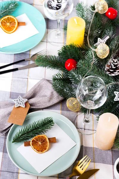 Fiestas de Navidad y Año Nuevo ajuste de mesa con naranja seca y canela en un textil gris. Comedor decorado con conos de pino, ramas y velas —  Fotos de Stock