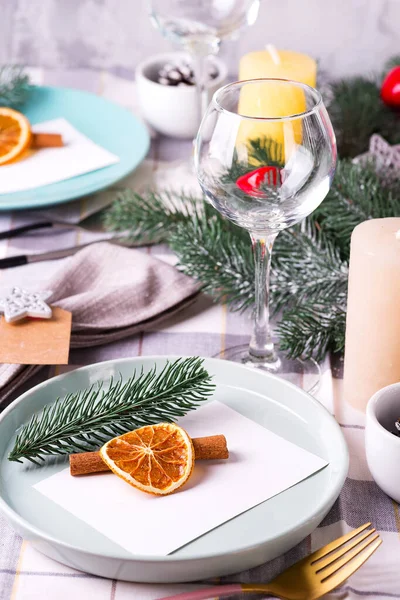 Fiestas de Navidad y Año Nuevo ajuste de mesa con naranja seca y canela en un textil gris. Comedor decorado con conos de pino, ramas y velas —  Fotos de Stock