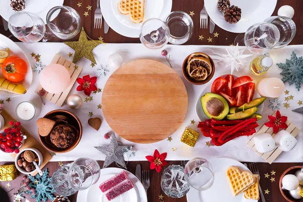 Karácsonyi asztal beállítása étellel egy tányéron és dekoráció sötét fa asztal, lapos laikus — Stock Fotó
