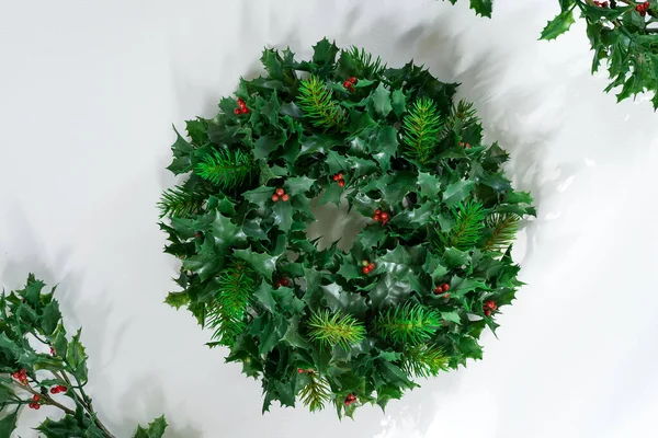 Photo of holly with red berries arranged in a wreath frame on a white background with shadow. — Stock Photo, Image