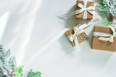 Beyaz zemin üzerinde kar köknar dalları ve güneş ışınları olan hediye kutuları. Noel kartı. Düz metin kopyalama alanı