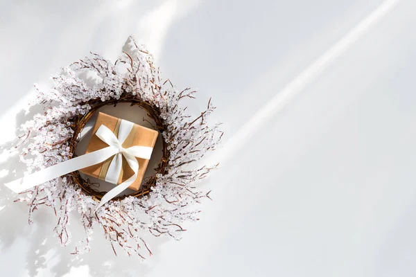 Caixa de presente de Natal e ramos de grinalda de geada no fundo branco com raios de luz solar, espaço de cópia plana leigos — Fotografia de Stock