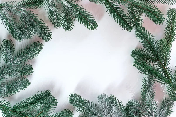 Fir branches frame in the snow with sunlight rayson a white background. Christmas background. Space for text. Top view. — Stock Photo, Image