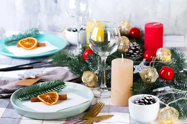 Fiestas de Navidad y Año Nuevo ajuste de mesa con naranja seca y canela en un textil gris. Comedor decorado con conos de pino, ramas y velas —  Fotos de Stock