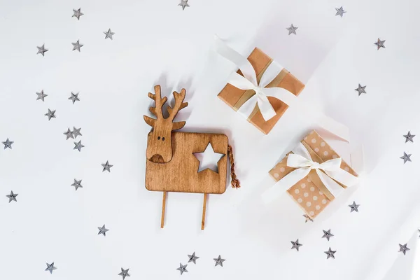 Pequeñas cajas de regalo con ciervos de madera vintage contra una estrella brillante fondo blanco celebración de Navidad . — Foto de Stock