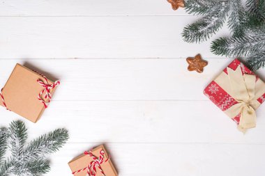 Beyaz ahşap zemin üzerinde kar ladin dalları ve yıldız kurabiyeleri olan hediye kutuları. Noel kartı. Düz metin kopyalama alanı
