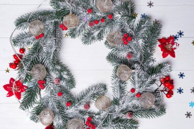 Beyaz ahşap arka planda köknar dalları ve dekor içeren Noel tebrik kartı. Selamlamalarınız için kopyalama alanı olan en üstteki görünüm