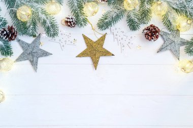 Noel ışık topları köknar ağacı dalı, koni ve oyuncak yıldızlar beyaz ahşap üzerinde, üst görünüm kopyalama alanı