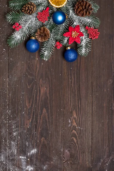 Різдвяна листівка з декором і гілкою ялинки на темному дерев'яному тлі. Вид зверху з місцем для копіювання ваших привітань — стокове фото