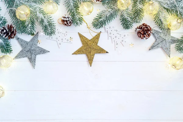 Bolas de luz de Navidad con rama de abeto, cono y juguetes estrellas en madera blanca, espacio de copia vista superior — Foto de Stock