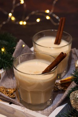 Koyu arkaplanda Tarçın Çubuğu ve açık renkli ev yapımı Beyaz Tatil Yumurtası. Noel içeceği